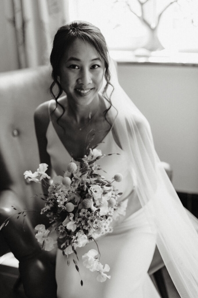 Schöne Braut in einem schlichten Spagetti-Träger Kleid (Slipdress) mit einem  locker gebundenem Brautstrauß aus Wiesenblumen.